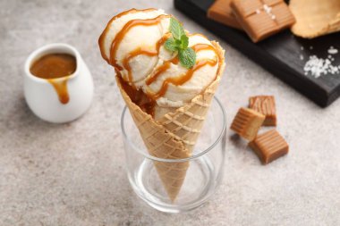 Tuzlu karamel soslu lezzetli dondurma ve gri masada naneli waffle. Yakın plan.