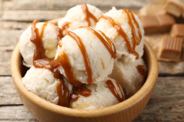 Tahta masadaki kasede karamel soslu lezzetli dondurma, yakın plan.