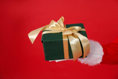 Kırmızı arka planda Noel hediyesi olan Noel Baba, yakın plan.