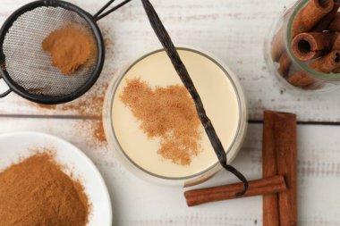 Lezzetli protein karışımı cam, tarçın ve vanilya kabuğu beyaz ahşap masa üzerinde, düz yatıyordu.