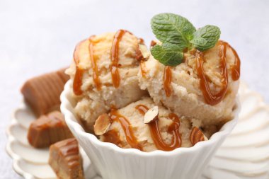 Karamel soslu lezzetli dondurma, badem ve nane şekeri, yakın plan.