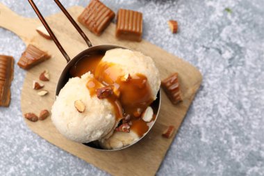 Karamel soslu lezzetli dondurma ve gri masada badem, düz uzanmış.