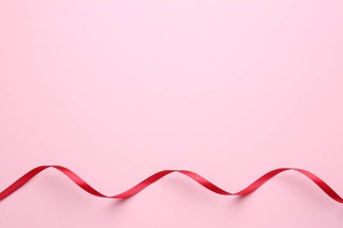 Pembe arka planda güzel kırmızı kurdele, üst manzara. Metin için boşluk