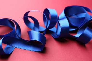 Kırmızı arkaplanda güzel mavi kurdele, yakın plan.