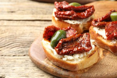 Krem peynirli lezzetli bruschettalar, güneşte kurutulmuş domatesler ve ahşap masada yeşil zeytinler, yakın plan. Metin için boşluk