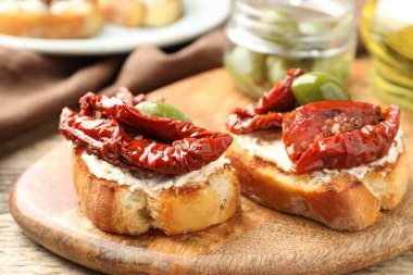 Krem peynirli lezzetli bruschettalar, güneşte kurutulmuş domatesler ve yeşil zeytinler masada, yakın plan.