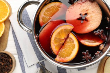 Lezzetli sıcak şarap tencerede ve malzemeler beyaz ahşap masada, düz yerde.