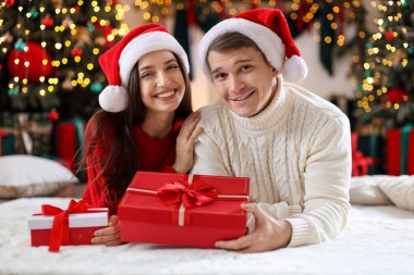 Noel Baba şapkalı mutlu çift evde Noel hediyeleriyle