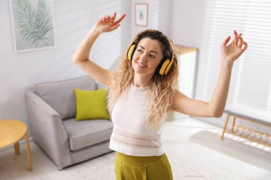 Kulaklıklı mutlu kadın evde dans ediyor.