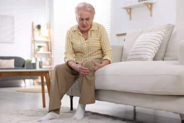 Evde diz ağrısı çeken yaşlı bir kadın. Romatizma belirtileri