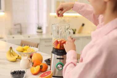 Mutfaktaki beyaz mermer masada blender ile nefis smoothie yapan kadın, yakın plan.