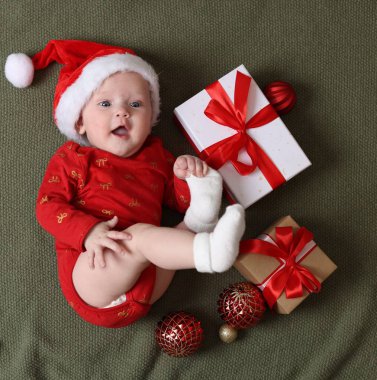 Noel Baba şapkalı şirin küçük bebek, Noel hediyeleri ve zeytin battaniyeli dekor, düz uzanma