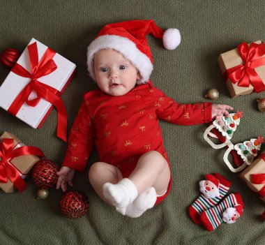 Noel Baba şapkalı şirin küçük bebek, Noel hediyeleri ve zeytin battaniyeli dekor, düz uzanma