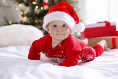 Evde, Noel Baba şapkası takıp yatakta takılan şirin bir bebek. Noel sezonu