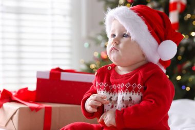 Noel Baba şapkalı şirin bir bebek ve evde yatağında hediye kutuları. Noel sezonu