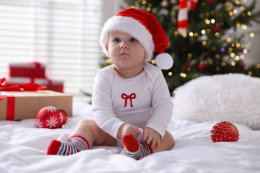 Noel Baba şapkalı şirin bir bebek ve evdeki yatakta takılar. Noel sezonu