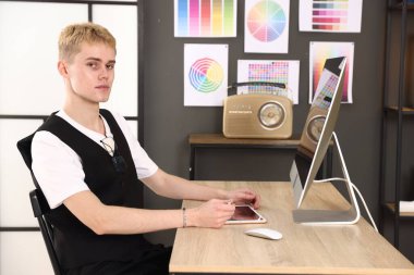 Ofisteki ahşap masada tablet üzerinde çalışan tasarımcı