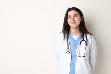 Beyaz arka planda steteskobu olan, tıp üniformalı bir doktor.