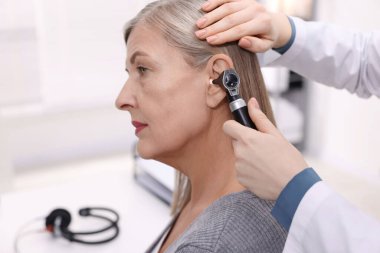 Duyma testi. Klinikte otoskopla hastanın kulağını muayene eden doktor, yakın plan.