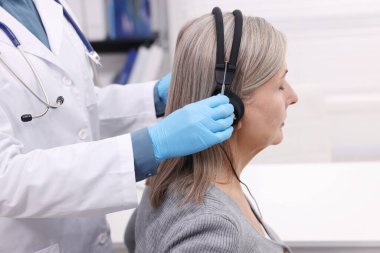 Duyma testi. Doktor klinikte hastanın işitsel kulaklıklarını ayarlıyor.