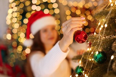 Noel Baba şapkalı güzel genç kız evde Noel ağacı süslüyor, seçici bir odak noktası var.