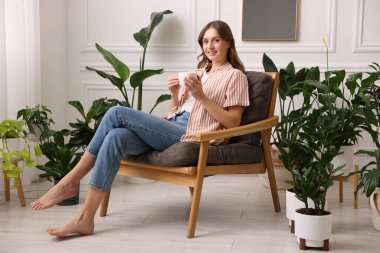 Evdeki koltukta bir fincan aromatik kahveli kadın.