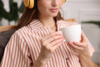 Evdeki koltukta bir fincan aromatik kahveli kadın, yakın plan.