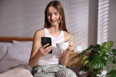 Evde telefonla kahve içen güzel bir kadın.