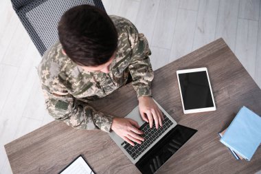 Askeri eğitim. Asker üniforması içindeki öğrenci ahşap masada öğreniyor.