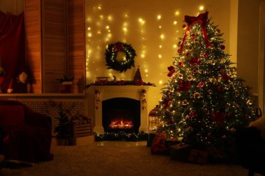 Güzel bir şömine, Noel ağacı ve karanlık odada şenlikli bir dekor. İç tasarım