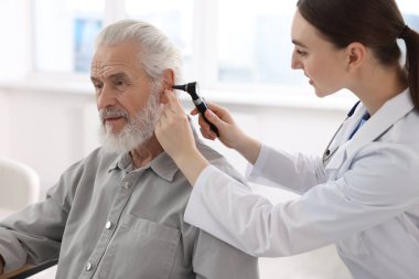 Duyma testi. Klinikte otoskopla hastanın kulağını muayene eden doktor.