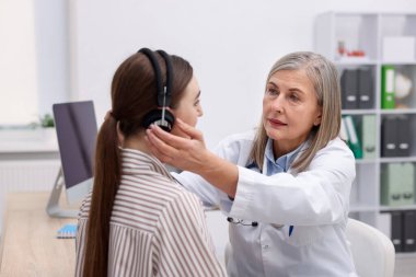 Duyma testi. Doktor klinikte hastanın işitsel kulaklığını ayarlıyor.