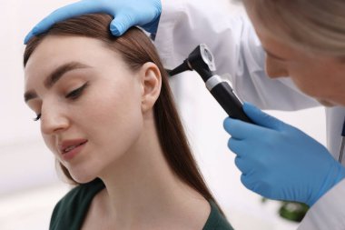 Duyma testi. Klinikte otoskopla hastanın kulağını muayene eden doktor, yakın plan.