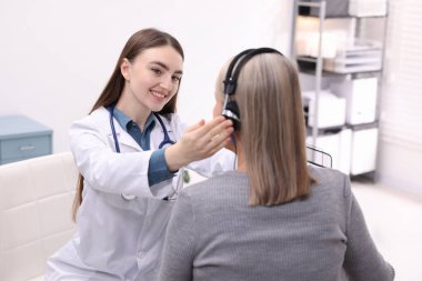 Duyma testi. Doktor klinikte hastanın işitsel kulaklığını ayarlıyor.