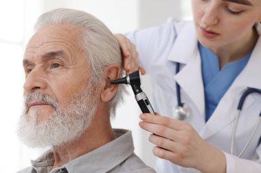 Duyma testi. Klinikte otoskopla hastanın kulağını muayene eden doktor, yakın plan.