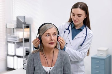 Duyma testi. Doktor klinikte hastanın işitsel kulaklığını ayarlıyor.