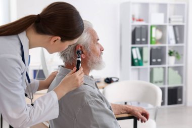 Duyma testi. Klinikte otoskopla hastaların kulaklarını muayene eden bir doktor. Metin için boşluk