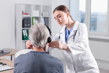 Duyma testi. Doktor klinikte hastanın işitsel kulaklığını ayarlıyor.