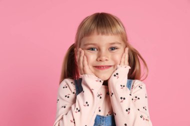 Pembe bir arka plan üzerinde gülümseyen küçük kız portresi