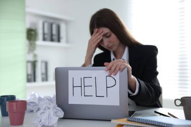 İşaretli kadın, masadaki dizüstü bilgisayarda yardım, seçici odaklanma