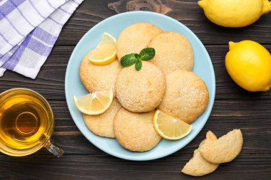 Lezzetli limonlu kurabiyeler ve siyah ahşap masa üzerindeki meyve dilimleri.