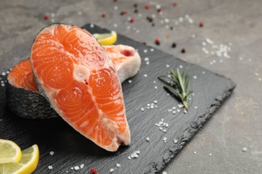 Gri masada baharatlı ve limonlu somon fileto parçaları, yakın plan. Metin için boşluk