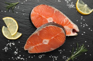 Baharatlı ve limonlu somon fileto parçaları siyah desenli masa, düz yatıyordu.