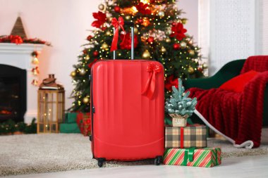 İçerideki bulanık ışıklara karşı fiyonklu bavul, hediyeler ve dekoratif köknar ağacı. Noel tatili