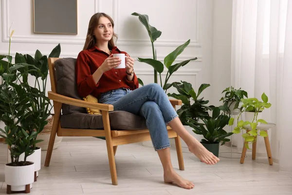 Evdeki koltukta bir fincan aromatik kahvesi olan kadın. Metin için boşluk