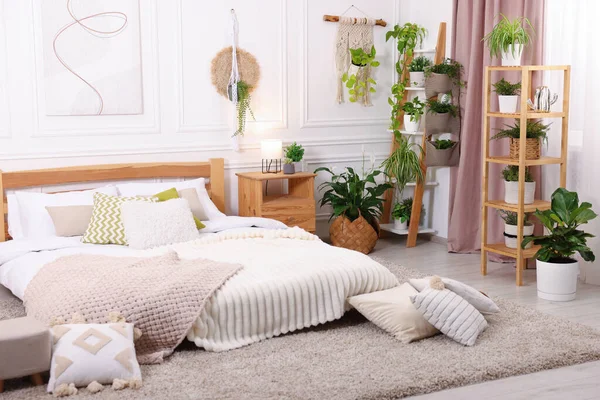 Rahat yatağı, lambası, yastıkları ve farklı çiçekleri olan güzel bir oda.