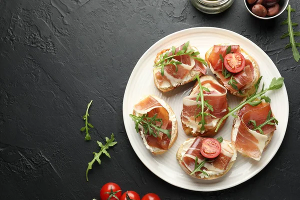 Krem peynirli nefis bruschettalar, prosciutto, domates ve roka koyu dokulu masa, düz yatak. Metin için boşluk