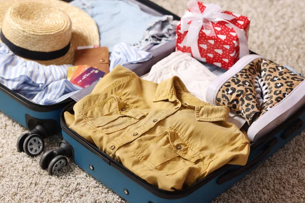 İçinde giysiler, hediye ve diğer eşyalar olan bavul kapalı alanda, yakın plan. Noel tatili