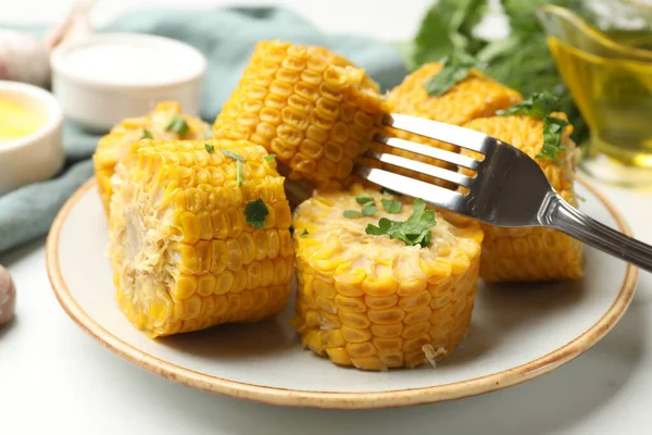 Beyaz masada servis edilen maydanozlu haşlanmış mısır koçanları.