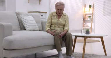 Evde diz ağrısı çeken yaşlı bir kadın. Romatizma belirtileri